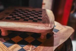 Two artisanal wooden chessboards with a black and wood checkered pattern, set in a refined interior with warm tones and intricate craftsmanship. photo