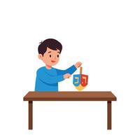 Boy playing with colorful dreidel at a wooden table in flat art vector