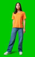 Model poses confidently in bright orange shirt and casual jeans against vivid green background during a studio shoot photo