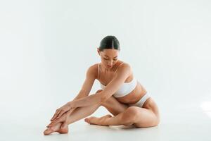 Sitting, on ,the floor.. Young woman with slim body type is in fitness clothes in the studio photo