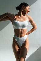 Shadow is on the body. Young woman in ,fitness clothes is in the studio photo