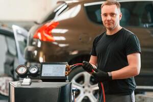With wires in hands. Man is works in the automobile repairing salon photo