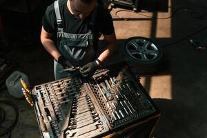 Tools for the repair in the box.. Man, is works in the automobile salon photo