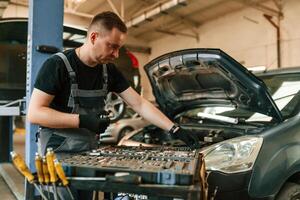 Under the hood,. Man is works in the automobile repairing salon photo