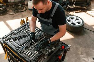 Standing by the toolbox.. Man is works in the automobile repairing salon photo