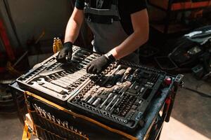 Tools, for the repair in the box. Man is ,works in the automobile salon photo