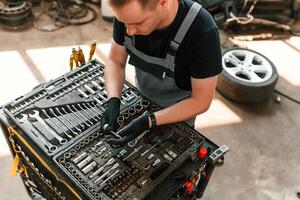 Standing by the toolbox,. Man is ,works in the automobile repairing salon photo