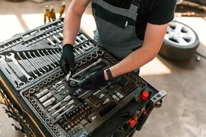 Standing, by, the toolbox. Man is works in the automobile repairing salon photo