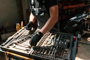 Tools for, the ,repair in the box. Man is works in the automobile salon photo