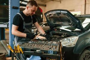 Under, the hood. Man, is works in the automobile repairing salon photo