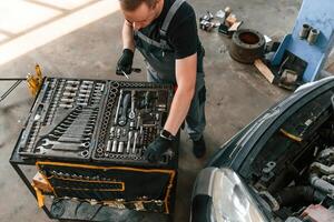Top view ,of employee that standing by the toolbox. Man is works in the automobile repairing salon photo