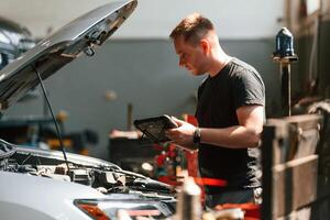 Using the tablet.. Man is works in the automobile repairing salon photo