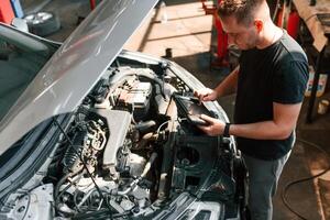 Under ,the hood. Man is works in the automobile repairing salon photo