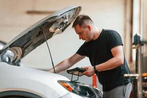 Holding the tablet. Man, is works in the automobile repairing salon photo