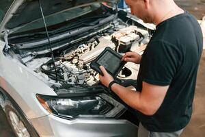 Holding the ,tablet. Man is works in the automobile repairing salon photo