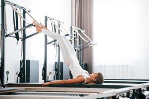 Lying down and, stretching legs., Young woman in fitness center is doing exercises photo