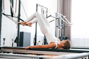 Lying down and stretching legs.,, Young woman in fitness center is doing exercises photo