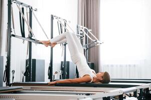 Lying down and stretching legs,. Young woman in fitness center is doing exercises photo