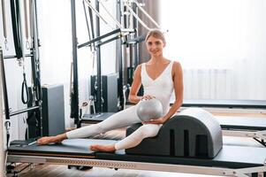 Holding ball in hands. Young ,woman, in fitness center is doing exercises photo