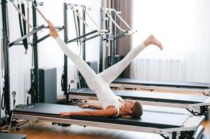 Lying down ,and stretching legs. Young woman in fitness center is doing exercises photo