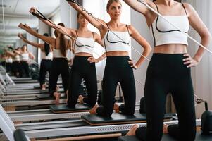 Against the mirror. Women ,in fitness center are doing exercises photo