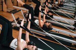 Lying ,down, in a row and doing stretches. Women in fitness center are doing exercises photo