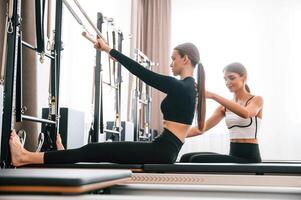 With ,the help of personal trainer. Women in fitness center are doing exercises photo