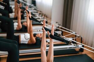Lying down, in a row and doing stretches. Women in fitness center are doing exercises photo