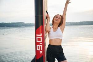 Smiling and enjoying ,the summer. Woman is standing with sup board against the lake photo