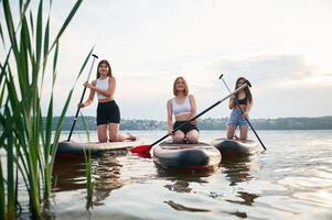 Front view. Young women are, on, sup boards in the lake photo
