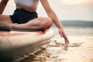 Touching, the water, close up view. Young woman is on sup boards in the lake photo