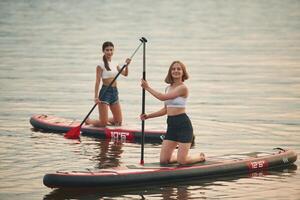 Young, women are on sup boards in the lake photo