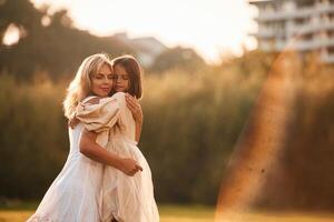 Embracing each other... Woman with her daughter is on the summer field photo