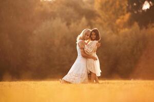 Embracing ,each other. Woman with her daughter is on the summer field photo