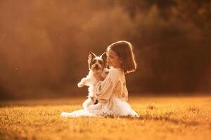 Sitting, on, the grass. Cute little girl is on the field with dog photo
