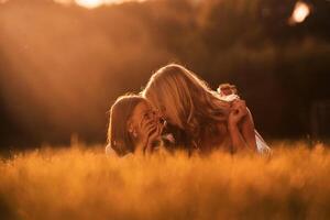 Illuminated ,by, sunlight, lying down. Mother with her daughter and cute dog are on the field outdoors photo