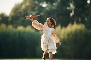 Running with, toy plane. Little girl is on the summer field outdoors photo