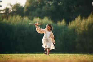 Running,, with toy plane. Little girl is on the summer field outdoors photo