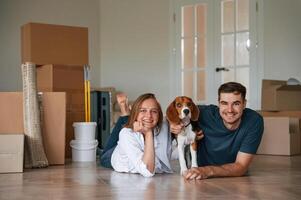 New owners are smiling. Young couple with dog are moving to new home photo