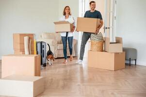 New, owners, are ,smiling. Young couple with dog are moving to new home photo