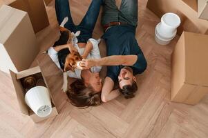 On the, floor,, lying down, top view. Young couple with dog are moving to new home photo