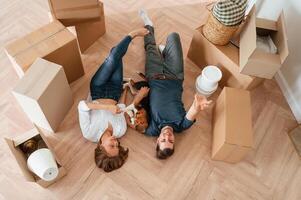 Happy young, couple with, dog are moving to new home. Lying down on the floor photo