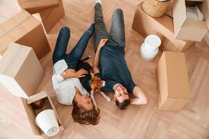 View from the top, lying down ,and ,resting. Young couple with dog are moving to new home photo