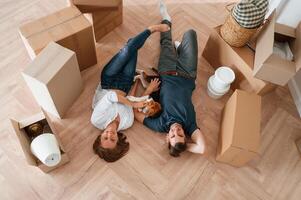Happy ,young couple ,with dog are moving to new home. Lying down on the floor photo
