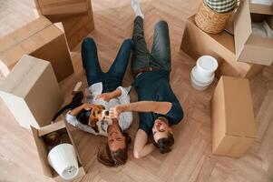On the floor, lying ,down, top view. Young couple with dog are moving to new home photo