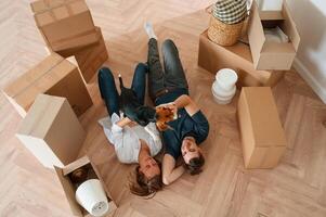 On, the, floor, lying down, top view. Young couple with dog are moving to new home photo
