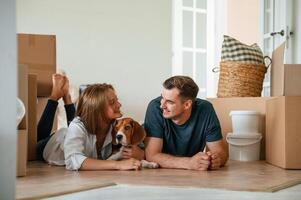 New owners are ,smiling. Young couple with dog are moving to new home photo