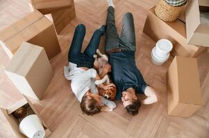 Between boxes,, lying down. Young couple with dog are moving to new home photo