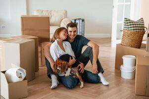 Front view. .,Sitting together. Young couple with dog are moving to new home photo