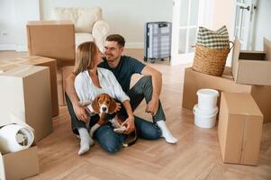 Conception of ,success. Sitting on the floor. Young couple with dog are moving to new home photo